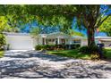 Inviting home with a manicured lawn and mature trees providing shade, creating a picturesque setting at 880 Phyllis Ave, Largo, FL 33771