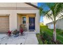 Charming front porch featuring a blue door, a chair, and lovely landscaping including a small palm tree at 12775 Maple Bonsai Dr, Riverview, FL 33579