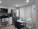 Eat-in kitchen featuring stainless steel appliances, tiled floors, and a glass-top dining table at 2555 Royal Pines Cir # A, Clearwater, FL 33763
