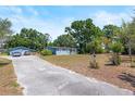 View of the home with a driveway leading up to a detached garage, surrounded by mature trees and greenery at 2805 Olavet Ct, Valrico, FL 33596