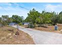 View of the home with a long driveway leading up to a detached garage and a chain-link fenced yard at 2805 Olavet Ct, Valrico, FL 33596