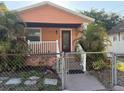 Inviting home featuring a charming porch, red door, and tropical landscaping at 2903 N 16Th St, Tampa, FL 33605