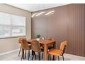 Modern dining room with stylish light fixture, wood accent wall, and seating for six around a wood table at 5519 Homewood Dr, Sarasota, FL 34232