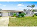 A well maintained single story home with a paved driveway, mature trees, and fresh landscaping on a sunny day at 5519 Homewood Dr, Sarasota, FL 34232
