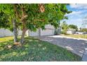 Paved driveway leading to a three-car garage, framed by a mature tree and greenery at 6130 Japonica Ct, New Port Richey, FL 34655