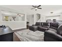 Open-concept living room features a dark leather sectional, dark hardwood floors, and gray walls at 11118 Running Pine Dr, Riverview, FL 33569