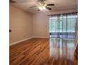 Open living room with wood flooring, ceiling fan, and sliding glass doors to outdoor space at 14061 Notreville Way, Tampa, FL 33624
