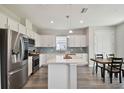 Modern kitchen featuring stainless steel appliances, white cabinets, a center island, and a dining area at 17652 Ramble On Way, Land O Lakes, FL 34638