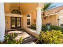 Elegant double front doors with decorative glass detailing and a covered porch with stately columns and lush landscaping at 30314 Fairway Dr, Wesley Chapel, FL 33543