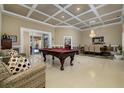 Open living space with a coffered ceiling, elegant chandelier, billiard table and access to the outdoor patio area at 30314 Fairway Dr, Wesley Chapel, FL 33543