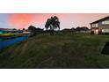 Beautiful backyard with a lush green lawn, a tranquil canal and open skies at sunset at 3847 Lighthouse Way # 3847, New Port Richey, FL 34652