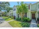 Inviting townhome featuring a landscaped front yard, mature trees, and complementary exterior color scheme at 6343 Osprey Lake Circle, Riverview, FL 33578