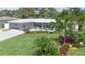 A single story home boasts a lush lawn, vibrant landscaping, covered porch, and a striking red front door for enhanced curb appeal at 7301 2Nd S Ave, St Petersburg, FL 33707