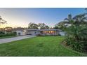 Charming single-story home with stone facade, manicured lawn, and colorful flower beds, complemented by a vibrant red front door at 7301 2Nd S Ave, St Petersburg, FL 33707