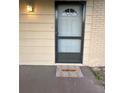 Front door with a screen door, welcome mat, and an outdoor light fixture at 7601 Como Dr, New Port Richey, FL 34655