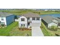 Aerial view of a two story home, featuring landscaping and a two-car garage at 9893 Branching Ship Trce, Wesley Chapel, FL 33545
