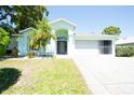 Charming single-story home with a well-maintained lawn, tropical landscaping, and a bright white garage at 10321 Ravines Dr, New Port Richey, FL 34654