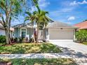 Charming single-Gathering home with well-manicured lawn, palm trees, and a two-car garage on a sunny day at 12327 Glenfield Ave, Tampa, FL 33626