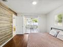 Bedroom with wood-look accent wall, sliding glass door to a screened patio, and a ceiling fan at 1390 S Hillcrest Ave, Clearwater, FL 33756