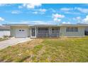 Inviting one-story home with a screened front porch and attached one-car garage, set against a beautiful blue sky at 1410 Lime St, Clearwater, FL 33756