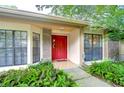 Charming home featuring a red front door and lush, green landscaping at 4215 Water Oaks Ln, Tampa, FL 33618