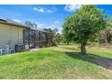 Manicured backyard featuring a screened-in patio with a hot tub and a swimming pool at 4323 Baynes Rd, North Port, FL 34288