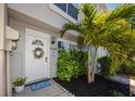 Charming entryway features a welcoming wreath, blue 'hello' mat, and lush palm trees, enhancing the curb appeal at 6600 121St Ave # 4, Largo, FL 33773