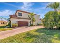 Charming two-story home showcasing a brown garage door, tiled roof, and a well-manicured lawn, capturing curb appeal at 10528 Bermuda Isle Dr, Tampa, FL 33647