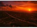 Stunning aerial view of a neighborhood, highway, and lake during a vibrant sunset at 1309 Pine Ridge E Cir # D3, Tarpon Springs, FL 34688