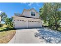 Charming two-story home with a spacious driveway and a three-car garage, landscaped for curb appeal under a bright blue sky at 13421 Sydney Rd, Valrico, FL 33594