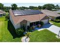 Aerial view of a well-maintained house with solar panels, landscaped yard, and an attached garage at 1575 Wicklow Dr, Palm Harbor, FL 34684