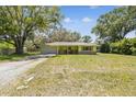Wide shot of a single story home featuring a green exterior, a front yard, and mature shade trees in the neighborhood at 16044 Stur St, Brooksville, FL 34604
