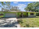 A charming single-story home showcases a colorful green exterior, a garage, and a welcoming front porch at 16044 Stur St, Brooksville, FL 34604