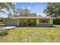 Charming single-story home with a colorful green exterior, stone accents and a welcoming front porch with rocking chairs at 16044 Stur St, Brooksville, FL 34604