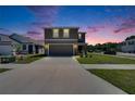 Two story home featuring a two car garage and manicured lawn at dusk at 16894 Delia St, Wimauma, FL 33598