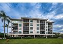 Multi-story waterfront condo building boasting lush lawn, mature palms, and classic architecture under a partly cloudy sky at 1806 Mariner Dr # 112, Tarpon Springs, FL 34689