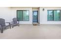 Outdoor patio area with two chairs, neutral flooring, and a view into the home through the sliding glass entry door at 1806 Mariner Dr # 112, Tarpon Springs, FL 34689