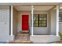 Inviting front porch with a red door, decorative pillars, and tile flooring detail at 2106 W Saint Isabel St, Tampa, FL 33607