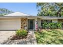 Welcoming home exterior boasting stone details, a blue front door, an American flag, and landscaped garden beds at 34 Hickory Ln, Safety Harbor, FL 34695