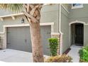 A close up of the townhome showcasing the two car garage and the front entrance with landscaping at 5710 Grand Sonata Ave, Lutz, FL 33558