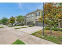 Street view of townhomes with attached garages, landscaping, and sidewalks, capturing a neighborhood setting at 5710 Grand Sonata Ave, Lutz, FL 33558