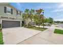 View of a two-story townhome featuring an attached garage, driveway, green space, and sidewalk at 5710 Grand Sonata Ave, Lutz, FL 33558