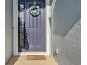 A blue front door with a wreath and a welcome mat that reads 'so happy you're here' at 7139 Steer Blade Dr, Zephyrhills, FL 33541