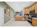 Bright kitchen featuring stainless appliances, tile floors, and convenient access to staircase at 8429 Hunters Fork Loop, Ruskin, FL 33573