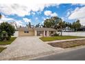 Inviting single-story home with brick driveway, beautiful lawn, and a cheerful red front door at 1820 Massachusetts Ne Ave, St Petersburg, FL 33703