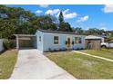Bright blue home featuring a carport and a well-maintained lawn on a sunny day at 1974 N Betty Ln, Clearwater, FL 33755