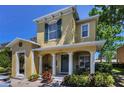 Charming two-story home featuring a covered front porch with decorative columns and lush landscaping at 2574 Hidden Cove Ln, Clearwater, FL 33763