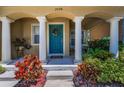 Inviting front porch adorned with columns, a wreath on the door, and vibrant landscaping at 2574 Hidden Cove Ln, Clearwater, FL 33763