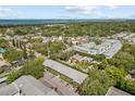 Aerial view of neighborhood with mature trees, houses, and ocean in the distance at 500 Glennes Ln # 205, Dunedin, FL 34698