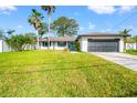 Beautifully landscaped home showcasing a spacious front yard, two-car garage, and welcoming curb appeal at 6070 Denver Ne St, St Petersburg, FL 33703